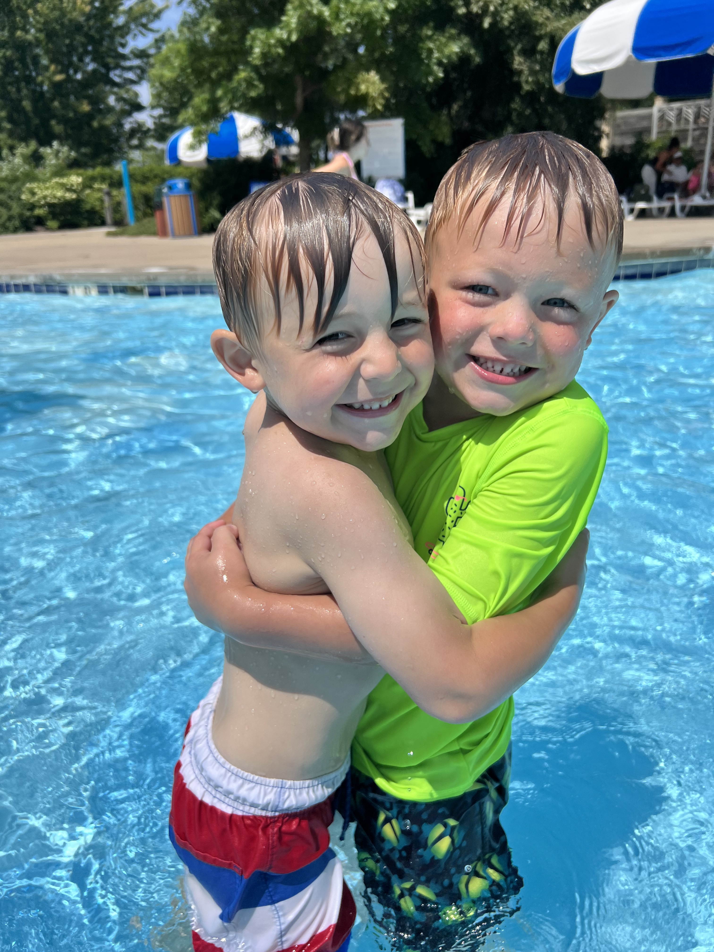 Two children hugging and smiling while in a pool